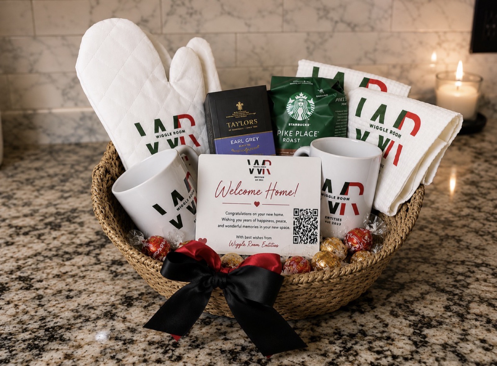 Branded closing gift basket containing logo mugs, oven mitts, waffle-weave kitchen towels, coffee, tea, chocolates and a Welcome Home card